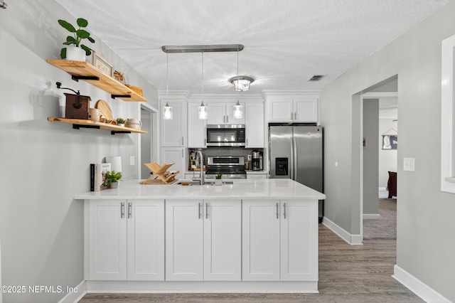 2599 Sandy Hollow Dr, Middleburg, FL 32068 - kitchen with appliances with stainless steel finishes, open shelves, a peninsula, white cabinets, and light wood finished floors