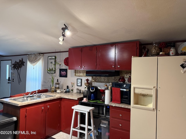 kitchen with red cabinets, black microwave, a sink, a peninsula, and white fridge with ice dispenser