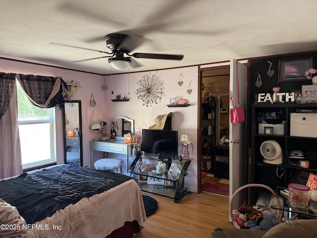 bedroom with a ceiling fan, a textured ceiling, and wood finished floors