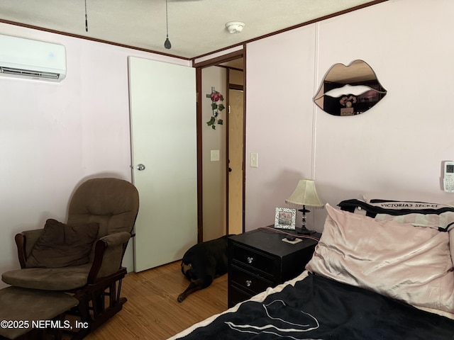 bedroom featuring a wall mounted air conditioner and wood finished floors