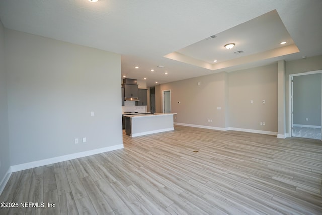 unfurnished living room featuring baseboards and a raised ceiling