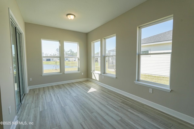 empty room featuring light wood-type flooring and a healthy amount of sunlight