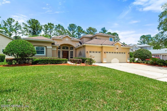 mediterranean / spanish home with stucco siding, an attached garage, concrete driveway, and a front lawn