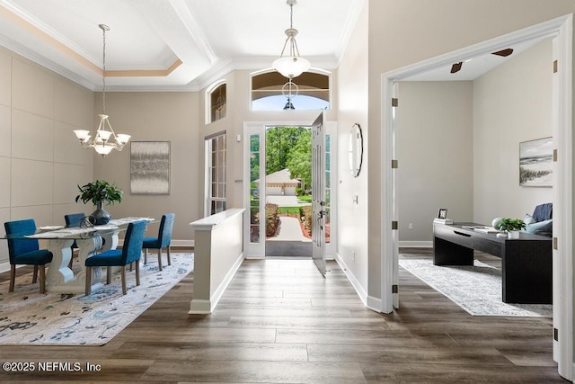 foyer entrance with crown molding, a chandelier, dark wood-style flooring, baseboards, and a high ceiling