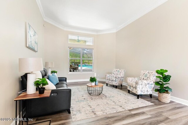 living area with crown molding, baseboards, and wood finished floors
