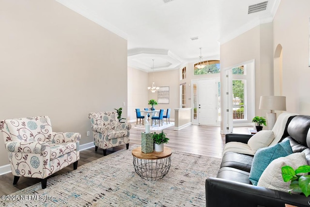 living area with arched walkways, a chandelier, wood finished floors, ornamental molding, and baseboards