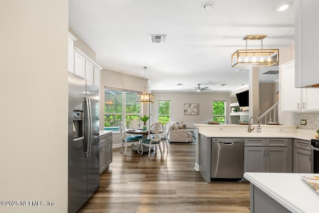 kitchen with stainless steel appliances, a sink, ceiling fan, open floor plan, and light countertops
