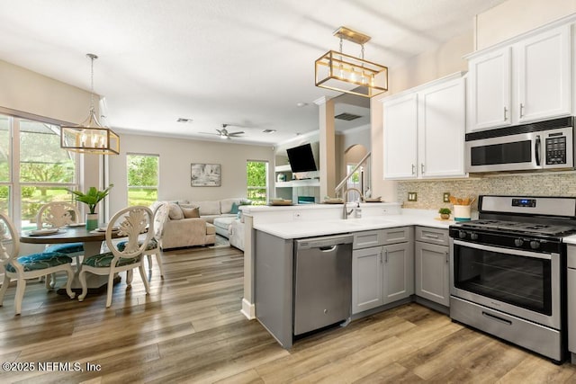 kitchen featuring appliances with stainless steel finishes, gray cabinetry, a chandelier, tasteful backsplash, and light countertops