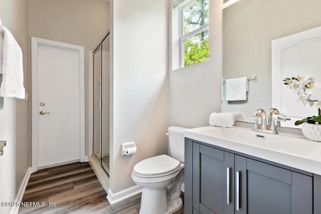 full bathroom with a shower stall, wood finished floors, toilet, vanity, and baseboards