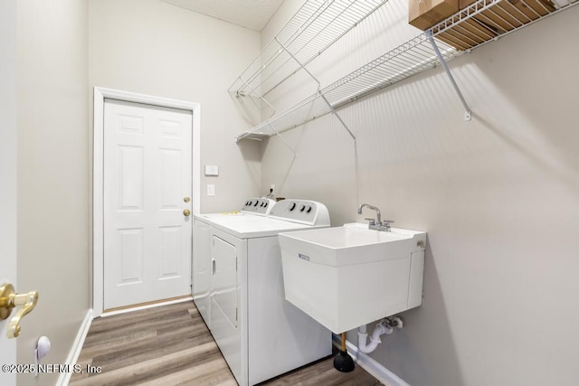 washroom with washing machine and clothes dryer, wood finished floors, and baseboards