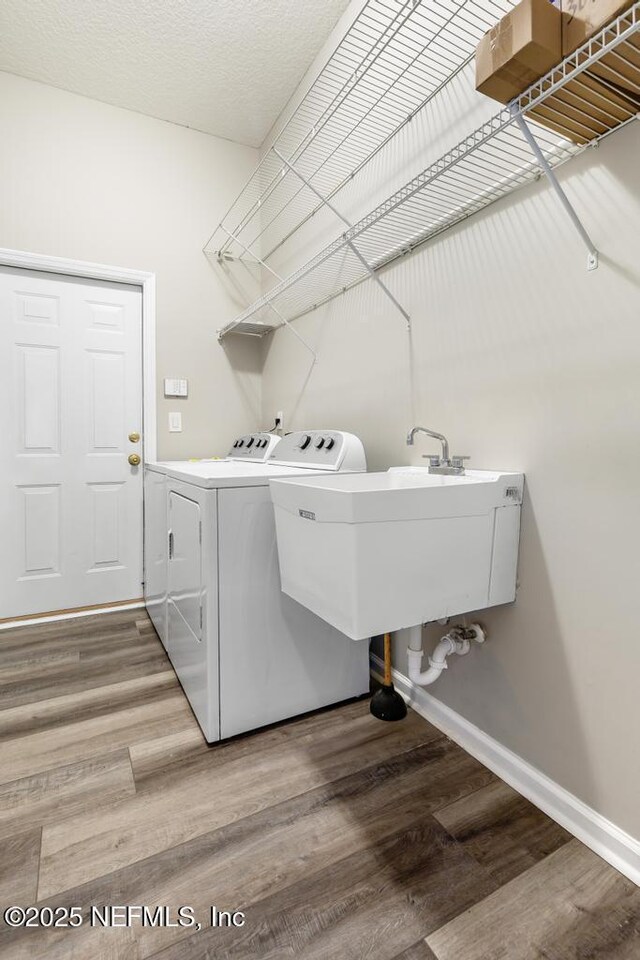 laundry room with washer and clothes dryer, wood finished floors, and baseboards