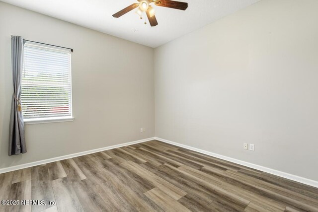 empty room with ceiling fan, wood finished floors, and baseboards