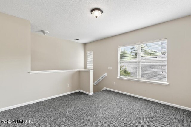 carpeted empty room with baseboards and a textured ceiling