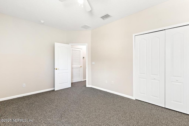 unfurnished bedroom with dark carpet, baseboards, a closet, and a ceiling fan