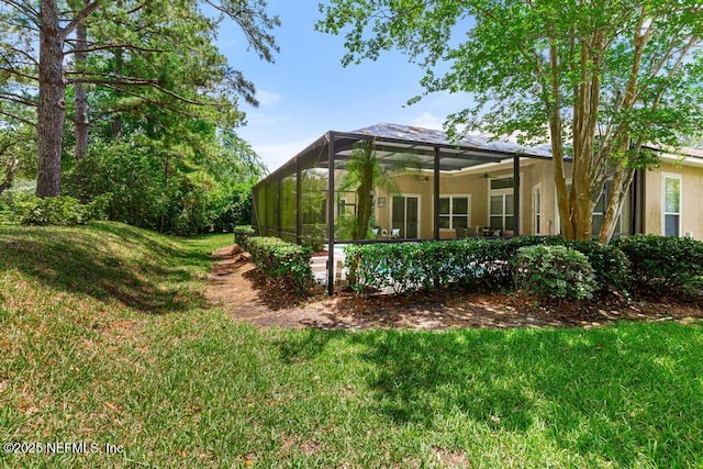back of house featuring a yard, stucco siding, and glass enclosure