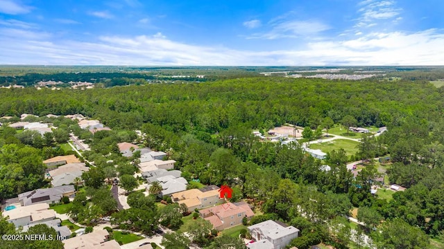 aerial view of property and surrounding area with a forest and nearby suburban area
