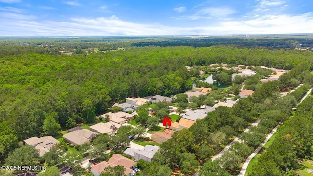 aerial view of property and surrounding area with a forest and nearby suburban area