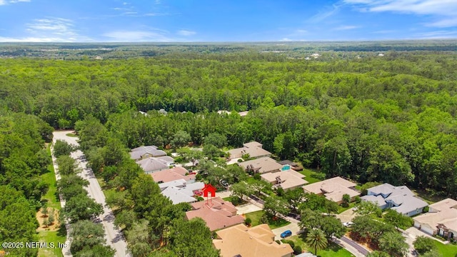 view of property location featuring a forest and nearby suburban area