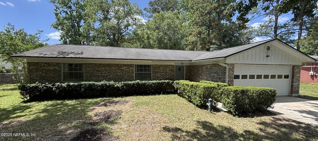 ranch-style home featuring a front yard, brick siding, board and batten siding, concrete driveway, and an attached garage