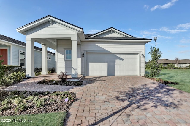 single story home with an attached garage, decorative driveway, and a front yard