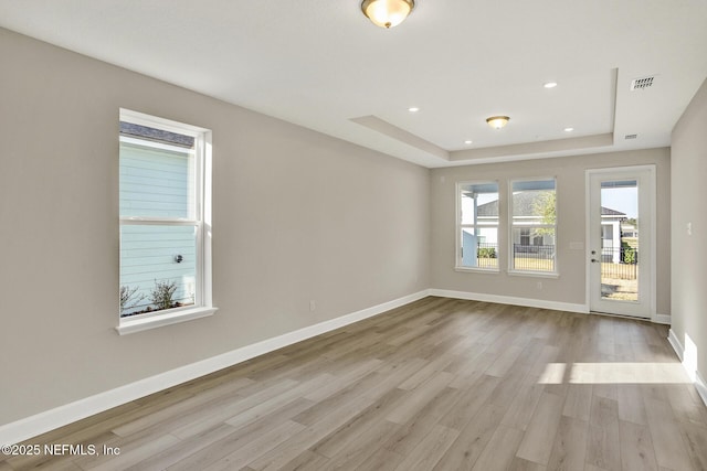 spare room featuring visible vents, baseboards, light wood-style floors, a tray ceiling, and recessed lighting