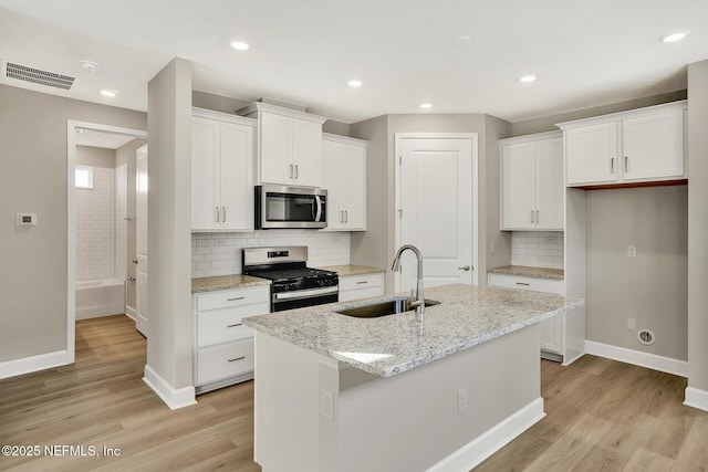 kitchen with baseboards, a sink, white cabinetry, and appliances with stainless steel finishes