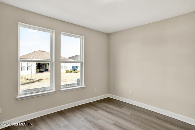 spare room featuring baseboards and wood finished floors