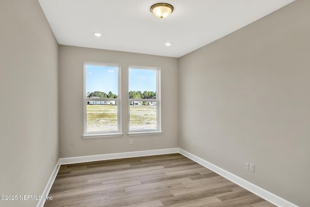 spare room featuring light wood-type flooring, recessed lighting, and baseboards