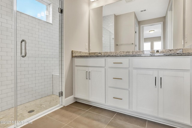 bathroom with tile patterned flooring, a stall shower, and a wealth of natural light