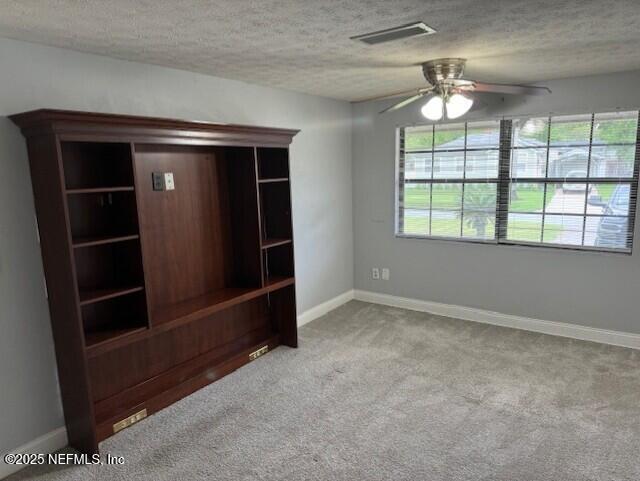 carpeted spare room with visible vents, a ceiling fan, a textured ceiling, and baseboards