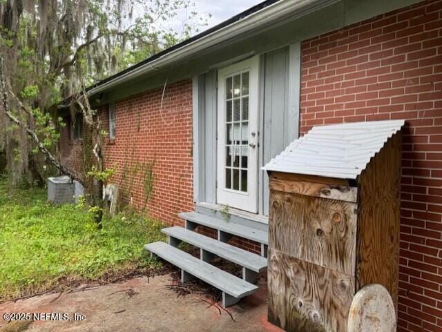 doorway to property with brick siding and cooling unit