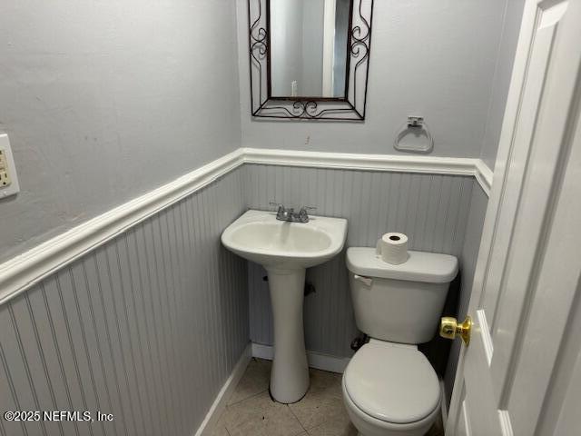 bathroom with tile patterned flooring, wainscoting, and toilet