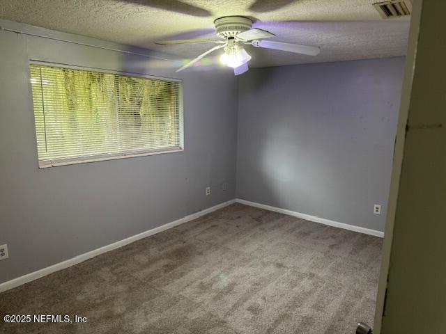 carpeted spare room with plenty of natural light, ceiling fan, a textured ceiling, and visible vents