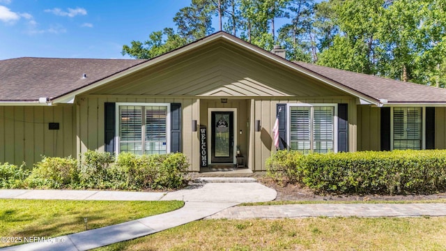 11136 River Creek Dr W, Jacksonville, FL 32223 - view of front facade featuring a chimney, roof with shingles, a front lawn, and board and batten siding