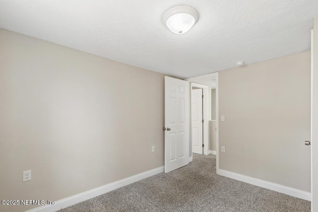 spare room featuring carpet floors, baseboards, and a textured ceiling