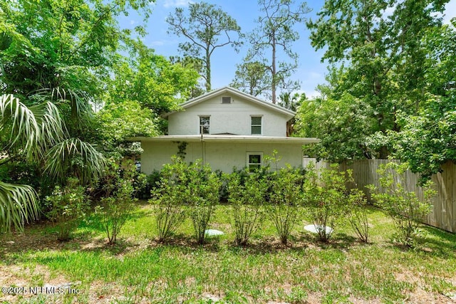 rear view of house with fence and stucco siding
