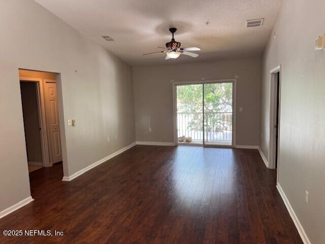 empty room with visible vents, baseboards, ceiling fan, and dark wood-style floors
