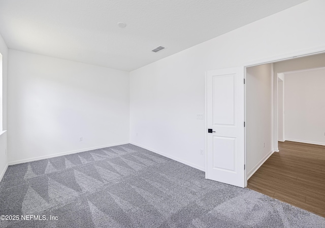 carpeted spare room featuring visible vents and baseboards