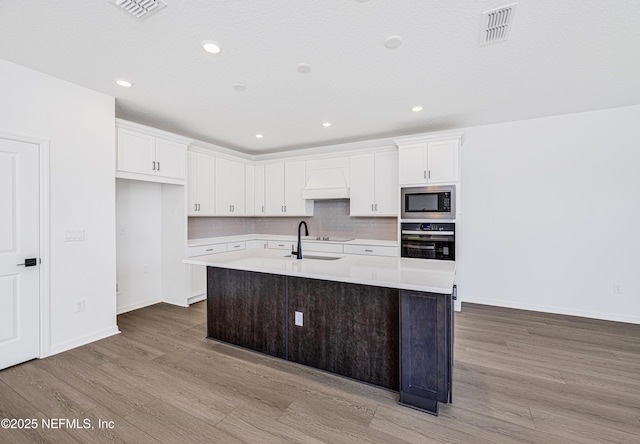 kitchen with wood finished floors, built in microwave, wall oven, and visible vents