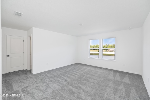 carpeted spare room featuring visible vents and baseboards