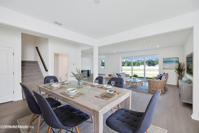 dining room with visible vents, wood finished floors, and stairway