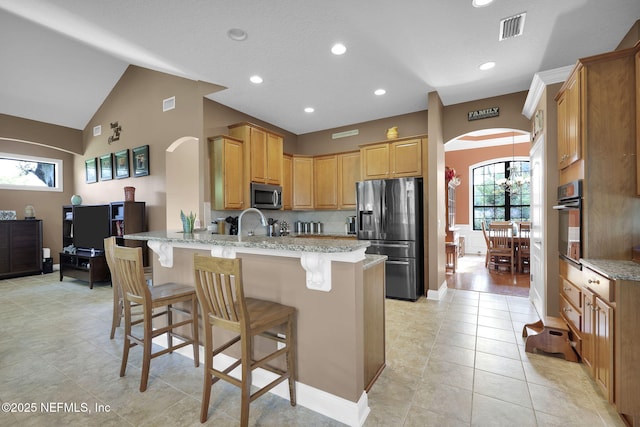 521 S Bridge Creek Dr, Saint Johns, FL 32259 - kitchen featuring stainless steel appliances, arched walkways, a peninsula, a breakfast bar, and light stone countertops