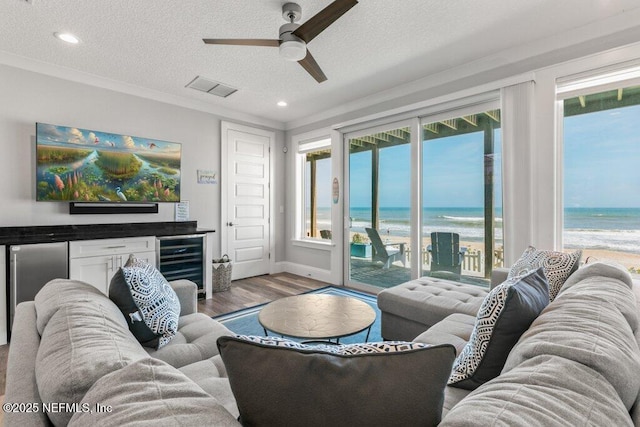 3083 S Ponte Vedra Blvd, Ponte Vedra Beach, FL 32082 - living area with wine cooler, a ceiling fan, wood finished floors, view of water and beach, and plenty of natural light