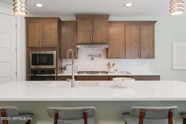 55 Rainbow Trout Ln, Ponte Vedra, FL 32081 - kitchen featuring stainless steel appliances, a sink, decorative backsplash, a breakfast bar area, and light stone countertops