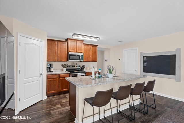 kitchen featuring dark wood finished floors, appliances with stainless steel finishes, brown cabinets, and light countertops