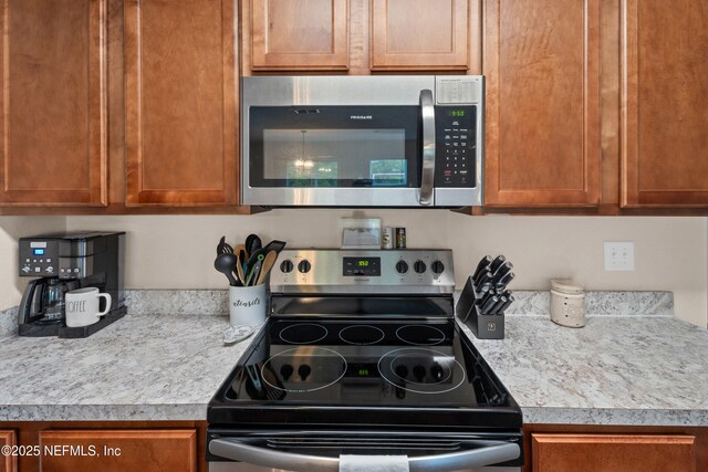 kitchen with brown cabinetry, light countertops, and stainless steel appliances