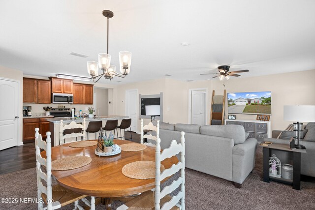 dining space featuring ceiling fan with notable chandelier, dark colored carpet, and visible vents