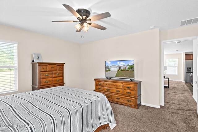 bedroom with stainless steel fridge with ice dispenser, carpet, a ceiling fan, baseboards, and visible vents