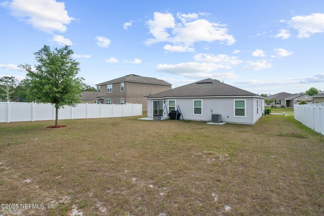 rear view of property with a fenced backyard, a yard, a shingled roof, and cooling unit