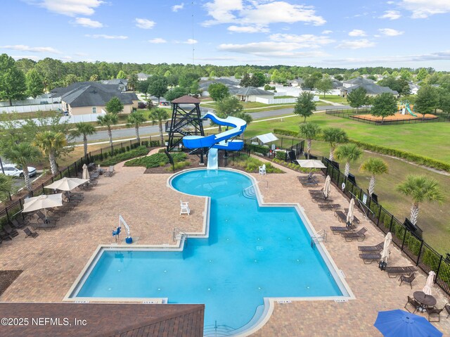 pool featuring fence, a water slide, and a patio area